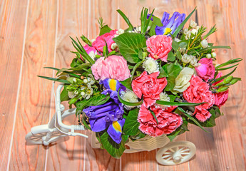 Floral arrangement with white bicycle and colored flowers roses, iris, chrysanthemums, Carnations, wood background
