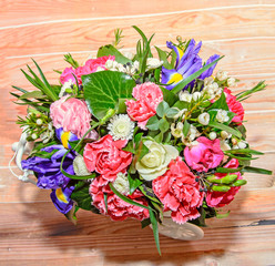 Floral arrangement with white bicycle and colored flowers roses, iris, chrysanthemums, Carnations, wood background