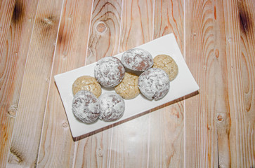 Round cookies stack on a white plate, powder sugar, wood background