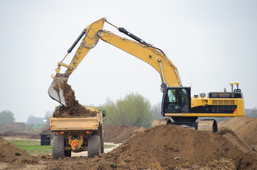 Construction site with big yellow excavators digging an piles of sand