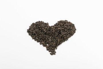 Black fried sunflower seeds on a white background.