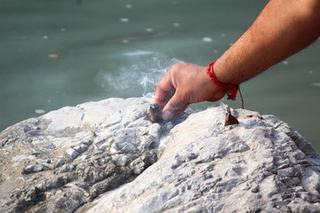 Indian man doing puja for ganga river. He put agarbati on the stone