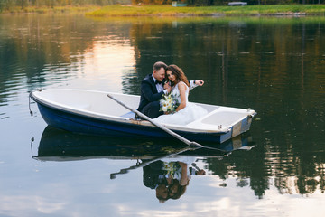 Fototapeta na wymiar The bride and groom in a rowboat on the lake