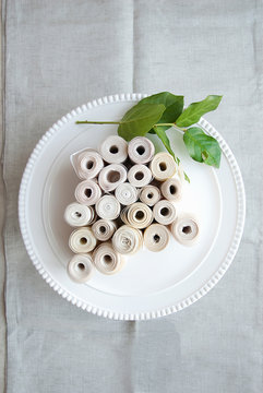 Rolls of fabric and leaf on plate