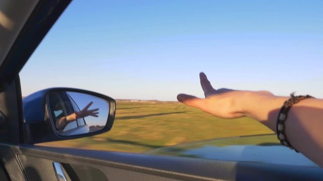 Sticking hand out of a riding car window slow motion