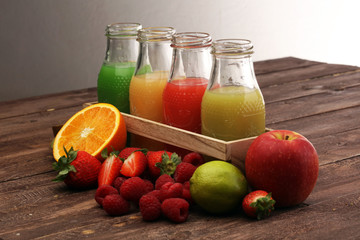 several bottles with fruit and berry juices smoothies and milkshakes , vintage wooden background, selective focus