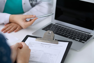  Close up of a doctor and  patient  sitting at the desk while physician pointing into laptop computer. Medicine and health care concept