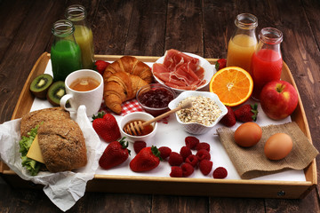 breakfast on table with bread rolls, croissants, coffe and juice