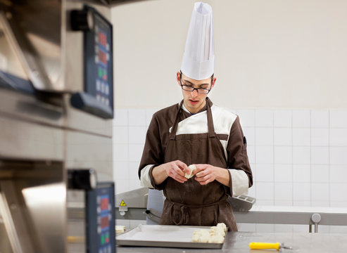 Baker shaping dough in kitchen