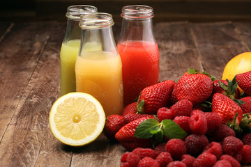 several bottles with fruit and berry juices smoothies and milkshakes , vintage wooden background, selective focus