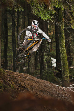 Mountain biker jumping muddy forest track
