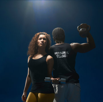 Studio Shot Of Young Woman And Personal Trainer With Hand Weights