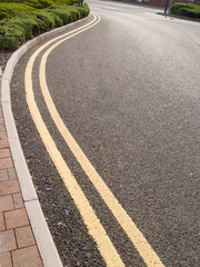 Double yellow lines on a section of curved road indicating car parking is prohibited.