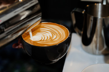pouring milk into a cup of coffee to make latte art