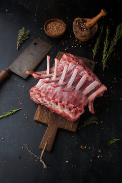 Raw rack of lamb with spices on a cutting board