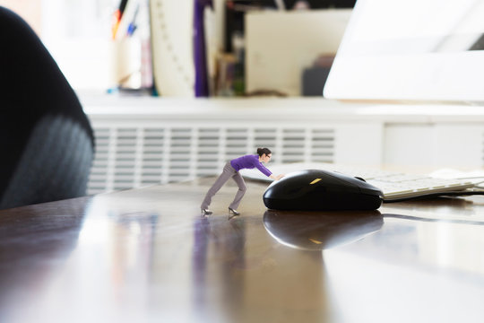 Businesswoman pushing large computer mouse on oversized desk