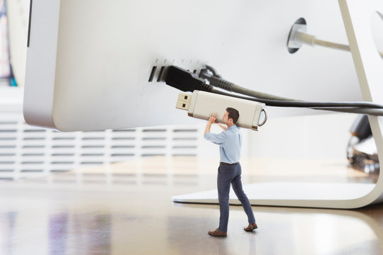 Businessman holding large USB stick next to oversized computer monitor