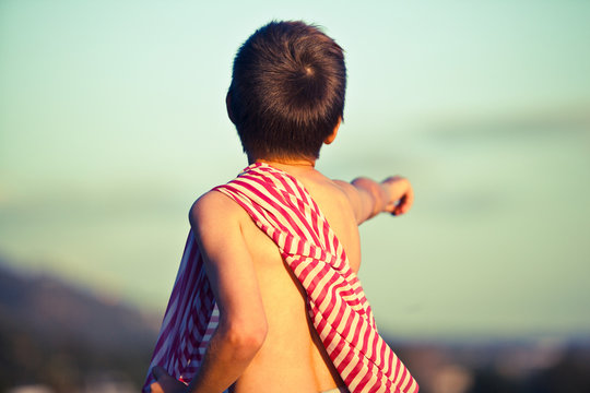 Boy pointing into distance with striped fabric on shoulder