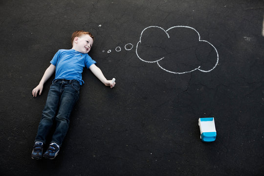 Boy lying on floor with chalk thought bubble