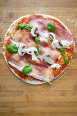 Traditional Italian pizza dough flat bread making tomato sauce mozzarella cheese salami prosciutto ham sausage basil hands chef wooden board kitchen preparation