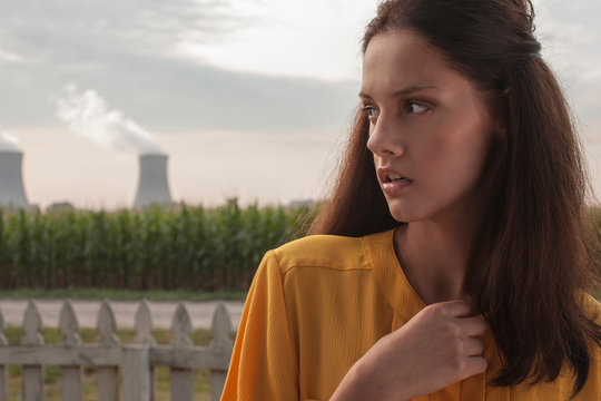 Pensive woman looking away with nuclear power station in background