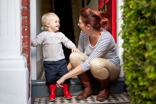 Little boy smiling after mother has helped him put on rubber boots
