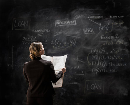 Businesswoman by blackboard holding newspaper