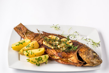 Grilled carp fish with rosemary potatoes and lemon, close up