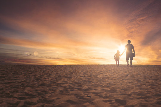 Little girl and father walking on sand