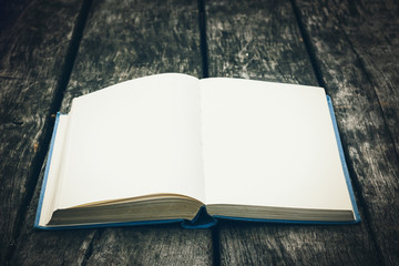 Old open book on a wooden table. Vintage composition. Ancient library. Antique literature. Fabulous atmosphere. Medieval and mystical background, retro style, religion. Close up view.