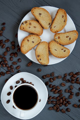 Cup of coffee, scattered coffee beans and toasted bread on a wooden background