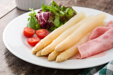 White asparagus with salad and ham on wooden background
