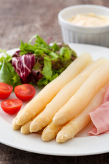 White asparagus with salad and ham on wooden background
