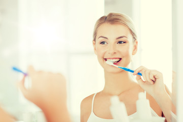 woman with toothbrush cleaning teeth at bathroom