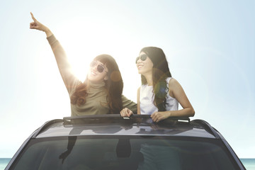 Two female looking something on car sunroof