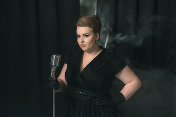 Retro 1950s female singer on smoky stage with black curtain.