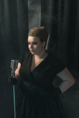 Retro 1950s female singer on smoky stage with black curtain.