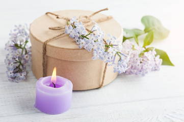 Fototapeta na wymiar Lit purple candle and lilac flowers