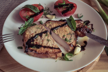 Vintage tone. Cut pork steak with sauce, mint, garlic and sliced tomato
