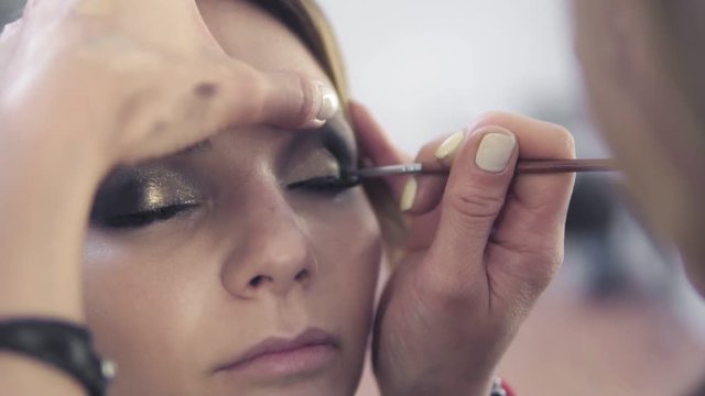 Closeup view of makeup artist applying eyeshadow on eyelid using makeup brush. Professional makeup. Slowmotion shot