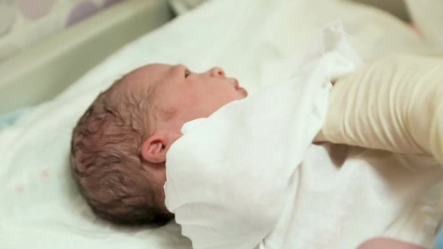 doctor puts a newborn with a clamp on the umbilical cord