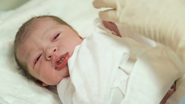 doctor puts a newborn with a clamp on the umbilical cord