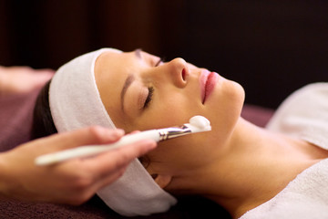 beautician applying facial mask to woman at spa