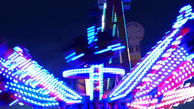 Close-up of attractions of fair, with colored flashing lights and turning at night.