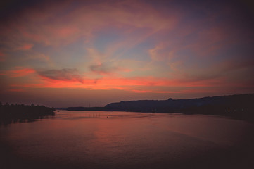View from the bridge over the river to a beautiful sunset with illuminated clouds
