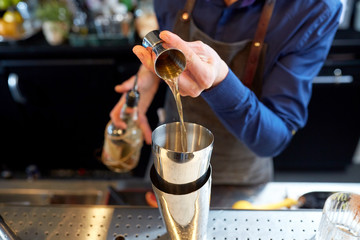 bartender with shaker preparing cocktail at bar