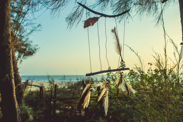 Amulet of sticks and feathers against the background of the ocean during sunset