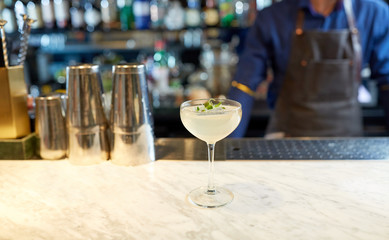 bartender and glass of cocktail at bar