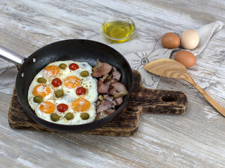 Fried eggs with bacon.olives and tomatoes a hearty breakfast. 