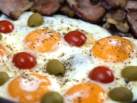 Fried eggs with bacon.olives and tomatoes a hearty breakfast. 